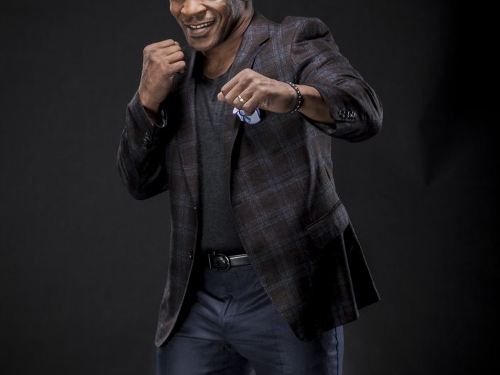 Jerry Metellus celebrity photographer. Portrait photography of superstar boxer Mike Tyson throwing a punch while well dressed and smiling.