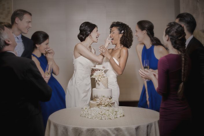 Jerry Metellus ad campaigns lifestyle photography. MGM Las Vegas LGBTQ Weddings. Portrait photography of the two brides cutting the cake and making a mess!