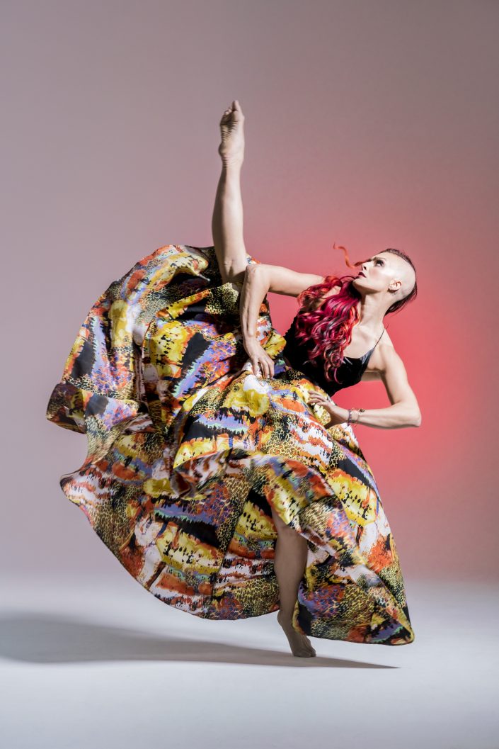 Jerry Metellus dance photography at JM Studios Las Vegas. Contemporary photography of a dancer in a vibrant skirt kicking one leg into the air.