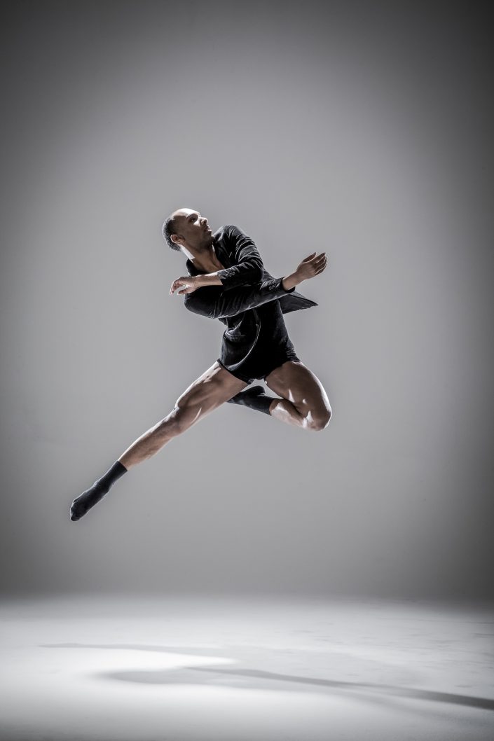 Jerry Metellus dance photography at JM Studios Las Vegas. Contemporary dance photography of a muscular dancer with a black button-up shirt and shorts dancing with black socks.